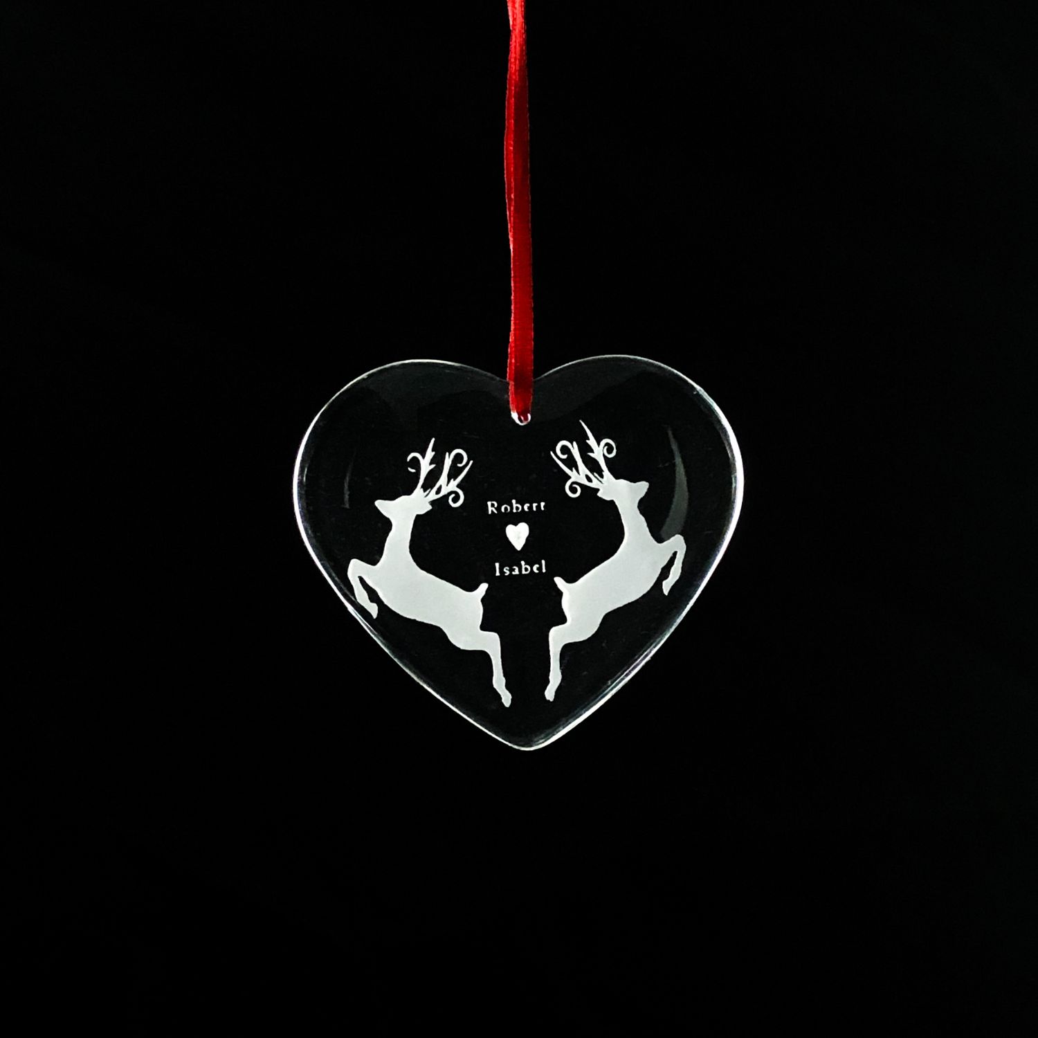 1 Heart-shaped crystal Christmas ornament with an engraved reindeer design, hanging from a red ribbon.