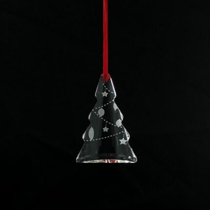 Christmas tree-shaped crystal ornament hanging from a red ribbon on a pine tree.
