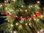 Long handmade rubber band garland featuring Santa's sleigh and all nine reindeer, decorated with bells and rhinestones, displayed on a Christmas tree.