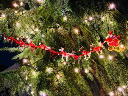 Long handmade rubber band garland featuring Santa's sleigh and all nine reindeer, decorated with bells and rhinestones, displayed on a Christmas tree.